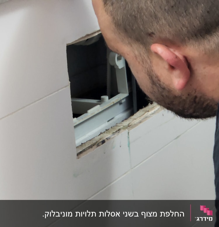אדם בודק צנרת מאחורי קיר פתוח